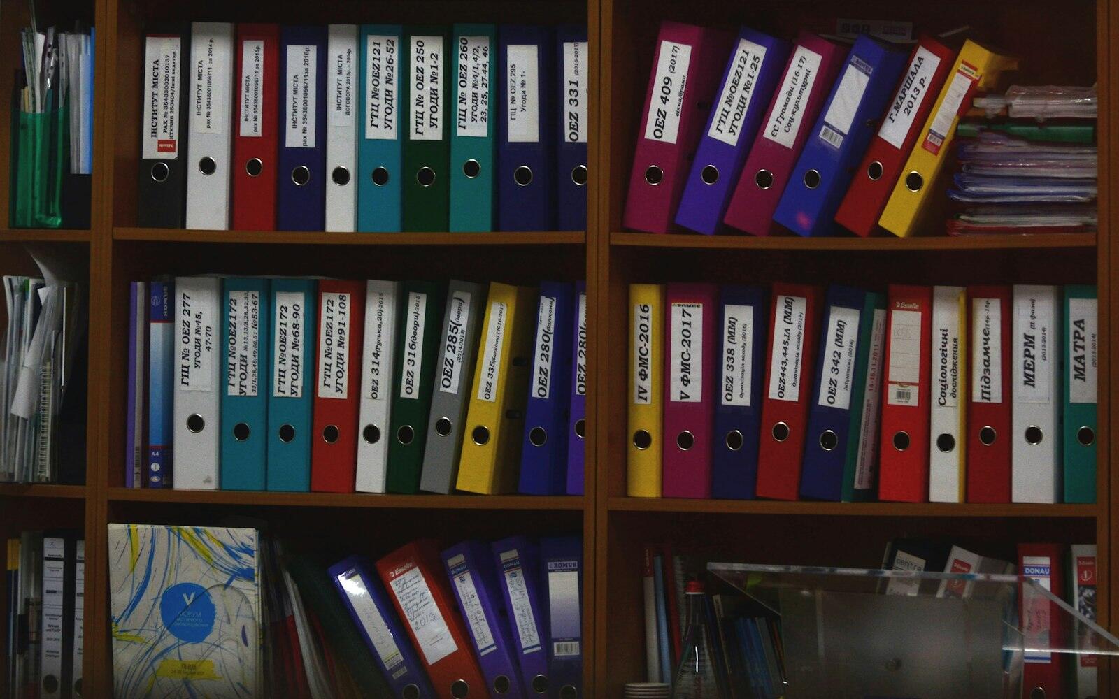 Scaffali di un archivio pieni di raccoglitori cartacei etichettati a mano
