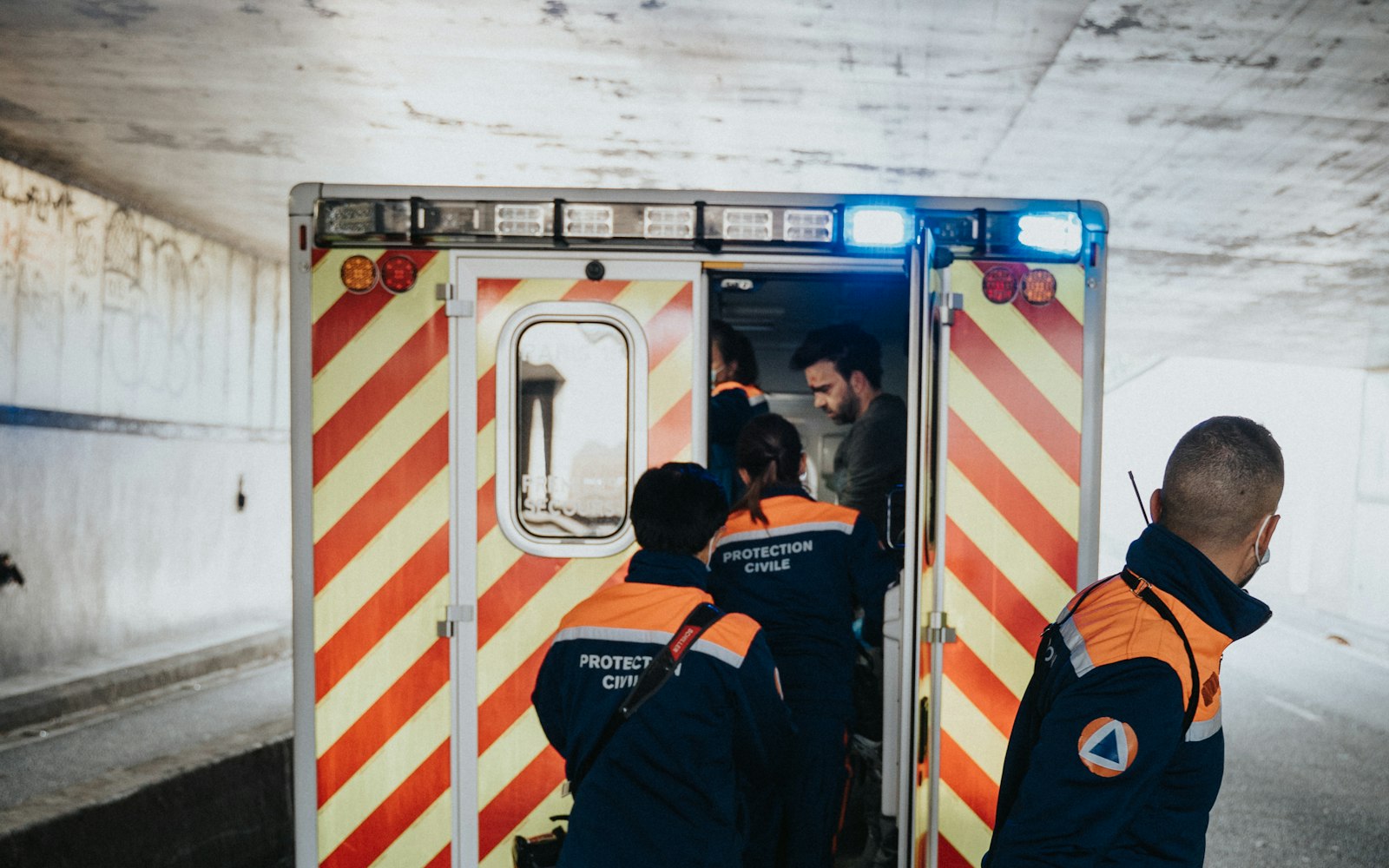 Equipaggio di protezione civile che carica una barella a bordo di un'ambulanza