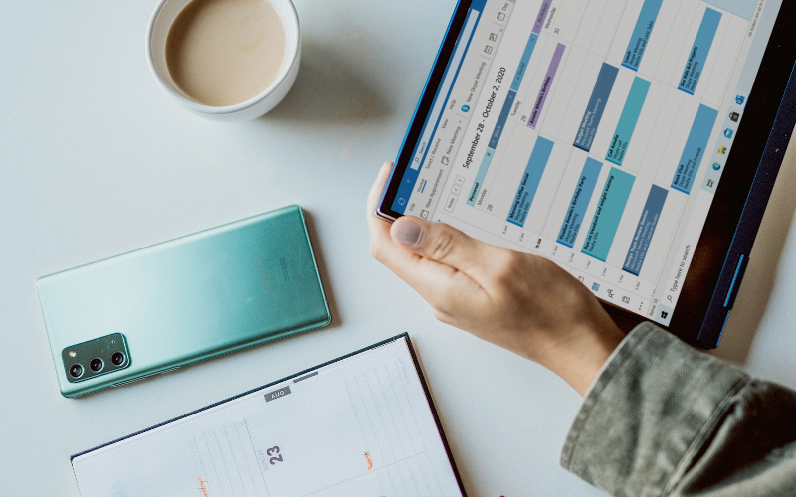 Calendario settimanale dei turni visualizzato su un tablet, accanto a uno smartphone e a un'agenda cartacea